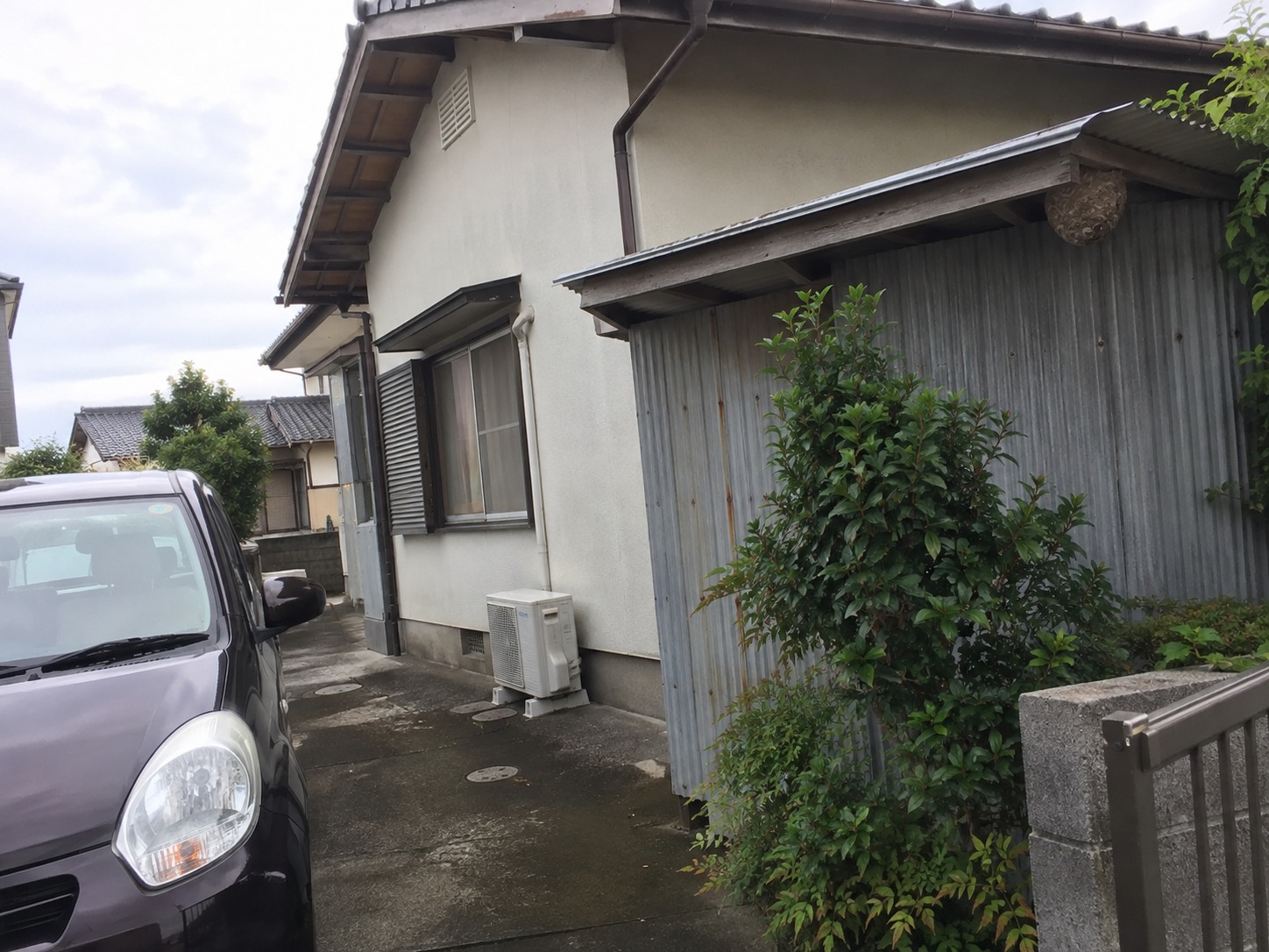 住宅の駐車場と収納庫の軒下が見える施工前の全体